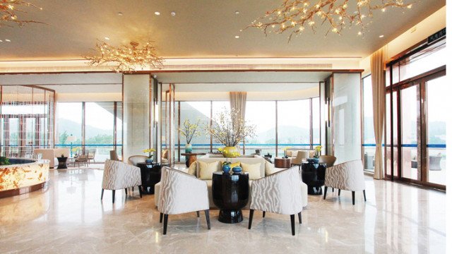 A modern luxury living room featuring a white sofa and armchairs, an ornamental rug, and a stylish wall art piece.