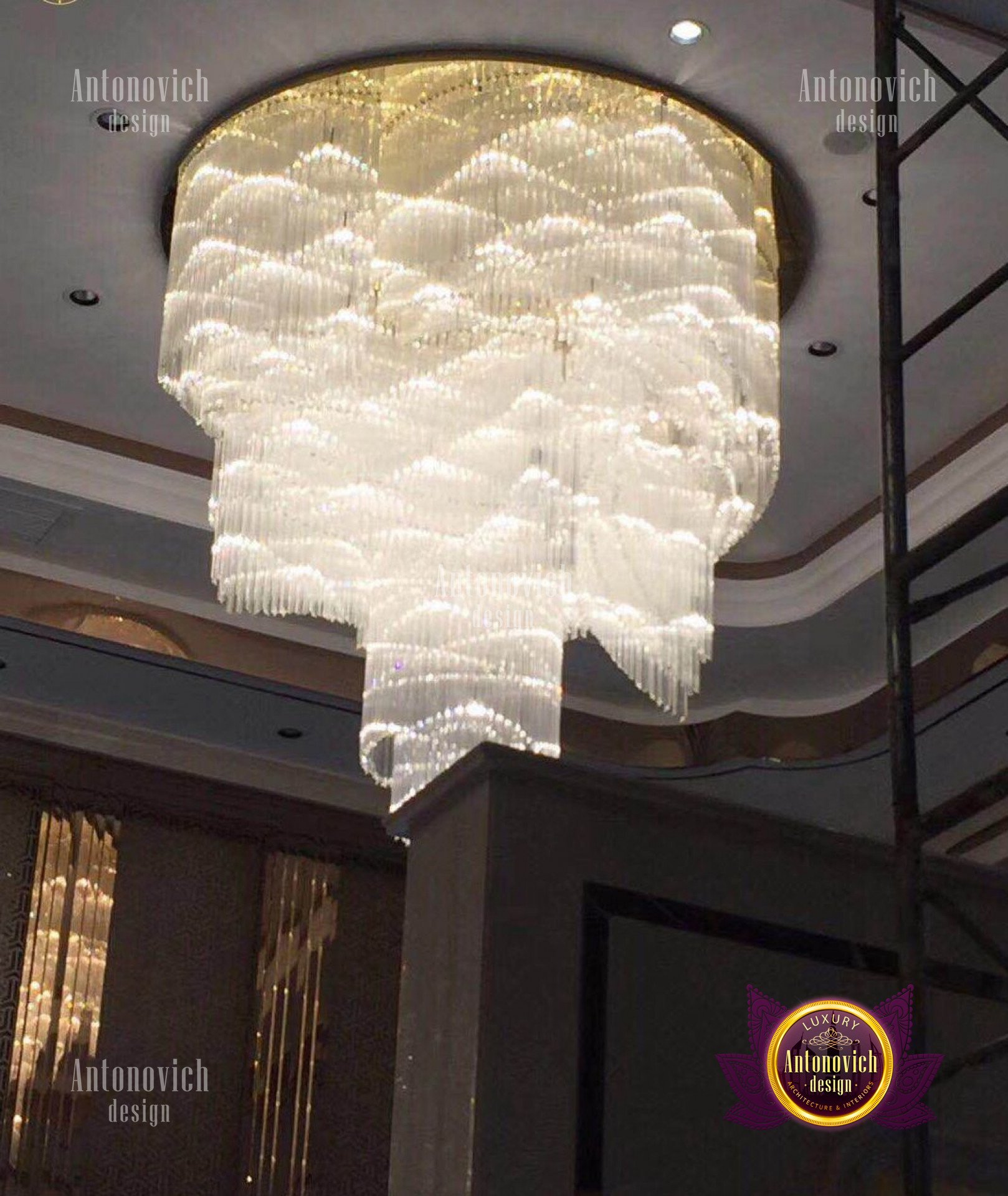 This picture shows a luxurious dining room with a beautiful white marble floor. The walls are lined with large mirrors, giving the room an air of opulence and grandeur. In the center of the room stands a large, white round dining table surrounded by a collection of elegant chairs with golden accents. Above the table hangs a dazzling crystal chandelier with intricate detail, and on the walls there are several golden wall sconces that provide a warm, inviting atmosphere.