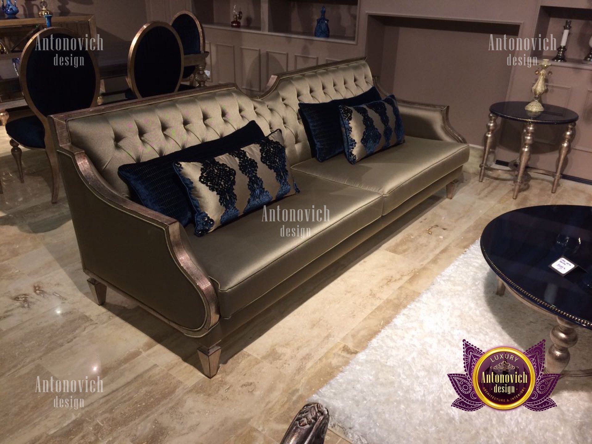 Interior design of modern living room featuring white walls, grey carpet, white ceiling, comfortable sofa and armchairs with green cushions, coffee table, pendant lighting fixtures, and a white bookshelf.