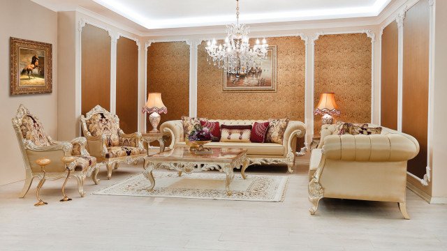 This picture shows a luxurious interior design concept of a living space. The room is decorated in warm tones with light wood accents. A large sofa is situated near the center of the room, complete with a matching armchair and coffee table. The walls are decorated with large abstract art pieces and there are several potted plants scattered around the room.