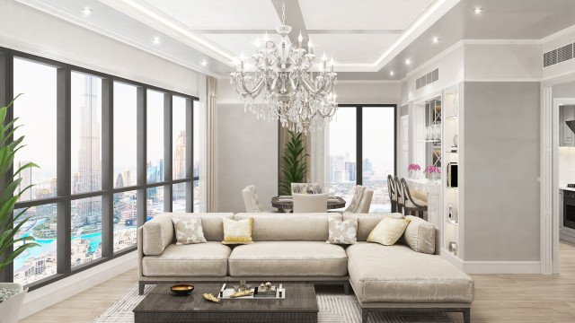 This picture shows an interior design featuring a modern and luxurious living room. The room has black walls with white accents, a gray leather sofa and chair set, and an accent wall of cream marble. There is a dark wood coffee table at center with a large, round floor lamp and a potted plant. Other touches of luxury include a vintage chandelier, a mirrored side table, and a grand mirror on the wall.
