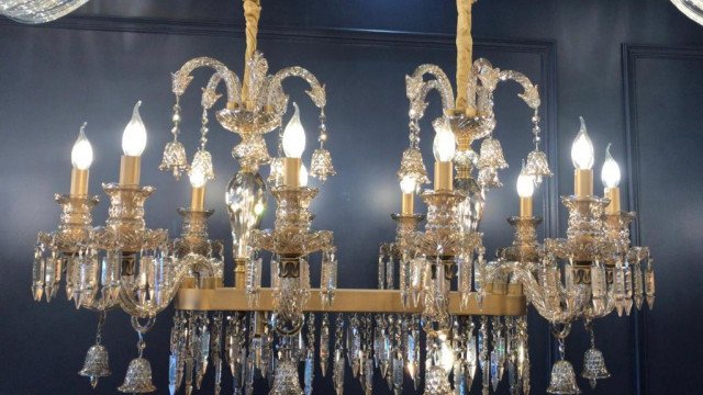 A room with a black and white checkerboard tile floor, an ornate chandelier, and a four poster bed.