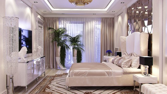 A large, luxurious bedroom with gold accents, patterned wallpaper and a crystal chandelier creating an opulent atmosphere.