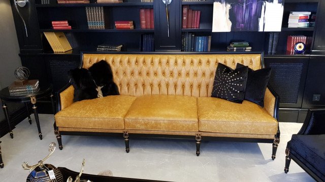 A grand living space with a luxurious velvet sofa set, complete with accent pillows, a plush rug on the floor, an ornate chandelier, and gold-framed artwork.