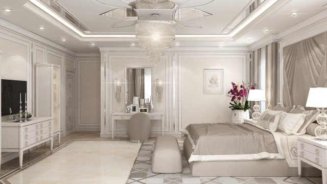 This picture shows a modern living room designed by Antonovich Design. The room features light gray walls with gray and white patterned chevron wallpaper, a plush white sofa, light gray tufted armchairs, a round glass accent table with a vase of white hydrangeas, and an elegant glass chandelier hanging from the ceiling. The room also includes a black round rug, two side lamps, a vintage dresser, and a large window on the adjacent wall, letting in plenty of natural light.
