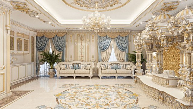 This picture shows a large luxury dining room with a round white marble table at the center. The walls are lined with two rows of square columns with gold accents, and a white sofa and armchairs surround the table. A crystal chandelier hangs from the ceiling, and there are several gold and white statues scattered around the room.