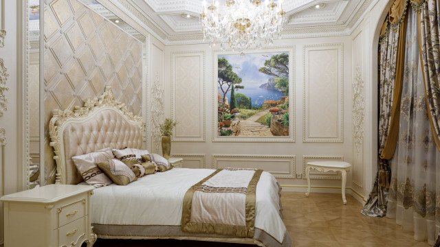 This picture shows a luxurious living room in an apartment designed by Antonovich Design. The room is decorated with a mix of classic and contemporary furniture and accessories, including a large crystal chandelier, plush velvet sofas, marble and wood tables, and decor pieces that are mostly grey and gold in color.