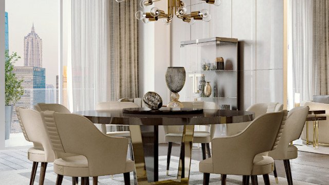 This picture shows a luxurious living room with classic elements. The walls are off-white and the furniture is upholstered in a rich burgundy fabric. There is a large decorative mirror on one wall, a large chandelier, an ornate couch and two armchairs in front of a marble fireplace, and a beautiful coffee table. There is also a white area rug on the floor and a pair of side tables with decorative lamps placed on them.