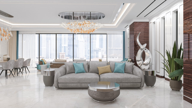 A modern luxury room interior with a marble floor, a wall decorated with golden wallpaper and large windows. A seating area consisting of an armchair, a pouf, and a sofa upholstered in cream fabric.