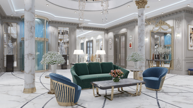 This picture shows a luxurious living room with a bright and airy design. The room includes elegant white walls, plush furniture with gold accents, and large windows that allow for plenty of natural light. An ornate crystal chandelier hangs from the ceiling to add additional glamour to the room. In the center of the room rests a round beige ottoman surrounded by greenery and decorative pieces.