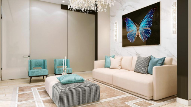 This picture shows a modern living room with a luxurious white sofa, two armchairs upholstered in a beige fabric, a round ottoman, and a glass coffee table that has a silver frame. The walls are painted white and decorated with framed artwork. The floor is covered in hardwood parquet planks and a sheepskin rug. There is also an intricate contemporary light fixture hanging from the ceiling.