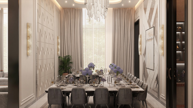 This picture shows a luxurious modern living room designed by Antonovich Design. The room features a curved seating area with a plush white sofa and accent chairs, an elegant center table, and a gallery wall showcasing modern artwork. The walls are painted a light beige that complements the warm wood tones of the furniture, and an ornate chandelier hangs from the ceiling for additional decoration.