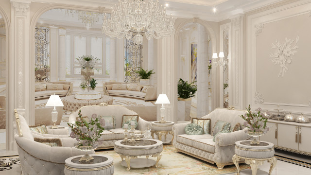 This picture shows a luxury bedroom designed and decorated by Antonovich Design. The room features light-colored walls and ceiling with a white marble floor, a contemporary platform bed with built-in nightstands, a velvet armchair, a large ottoman, a crystal chandelier, and several modern art pieces on the wall.