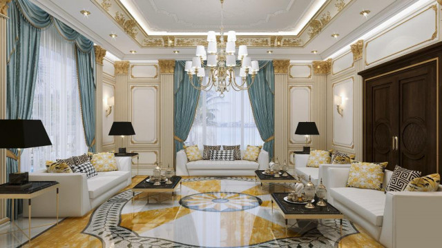 A large, elegant space with multiple seating areas and decorative lighting. The walls are finished in a combination of beige and white, with patterned wallpaper and built-in shelving. A plush yellow carpet covers the floor.
