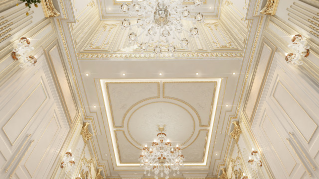 This picture shows a luxurious dining room interior design. The walls are painted in a cream color and feature a wide crown molding, as well as a tall baseboard with a floral pattern. The ceiling is adorned with a chandelier that is made of metal with glass droplets. The dining table is an ornate wood piece with two arm chairs, four side chairs, and a beautiful center piece. The floor is made of a dark hardwood with a geometric rug placed in the middle.
