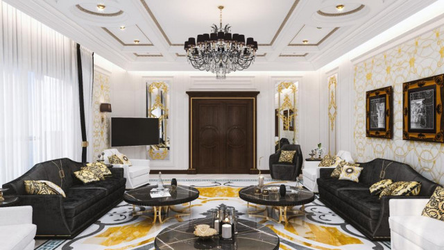 This picture shows a luxurious living room decorated with gold and white furnishings. The room has a large U-shaped white leather sofa with gold cushions, a glossy marble floor, two white armchairs upholstered in gold velvet, and a white coffee table with a glass top. The walls are adorned with large gold wall sconces and framed artwork, and there is an elegant chandelier hanging from the ceiling.