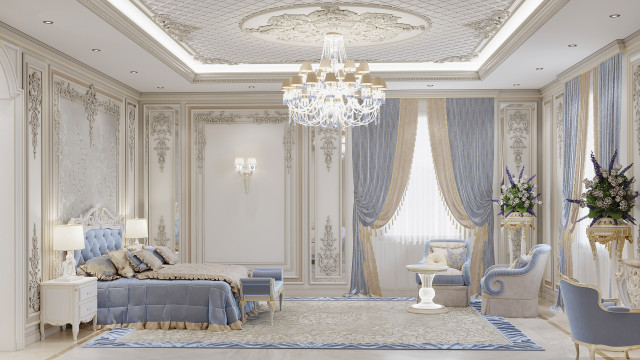 This is a modern interior design in a luxurious living room. The picture shows a contemporary style, with beautiful cream and beige colors. The room has a large plush sofa surrounded by several tables, an elaborate gold-framed mirror, and several decorative accents. The room also has a statement patterned light carpet which adds texture and richness to the area. There are two chandeliers, one in the ceiling in the center and another to the side, adding more sophistication to the space.