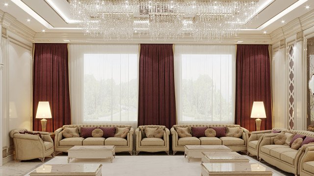 This picture shows a luxurious modern living room that has been designed by Antonovich Design. The room features a comfortable grey sofa, two matching armchairs, an elegant round brown table, and a large decorative mirror with a gold frame. There is a beige area rug on the floor, and two floor-to-ceiling windows with white shutters. The room also features various pieces of wall art, including a large abstract painting, and a few small potted plants for decoration.