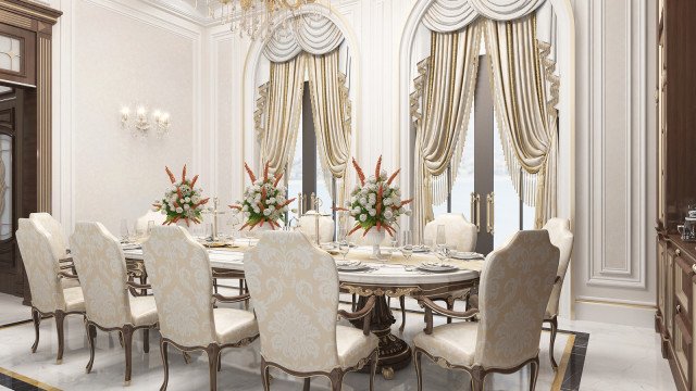 This picture shows a luxurious bedroom designed by the Antonovich Design studio. The walls are covered in cream and tan striped wallpaper, and the ceiling features a beautiful stucco accent that adds a luxurious look and feel. The four-poster bed is upholstered in a light gray fabric, and there is a matching chaise lounge on either side. A plush white rug lies beneath the bed and frames the bedding which includes several throw pillows in various shades of gray and silver. A decorative crystal chandelier hangs above the bed, adding a layer of sophistication to the space