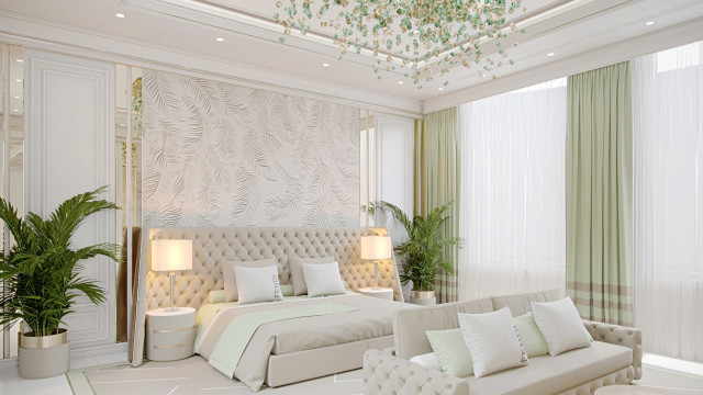 This picture shows a luxury bedroom designed with a modern aesthetic. The walls are painted a light shade of white, with gold accents and a light grey carpet to provide a subtle contrast. The ceiling is adorned with an ornate coffered design, while a chandelier hangs from the center. In the room are two chairs upholstered in a pale blue fabric, as well as a tufted ottoman and a large dresser topped with decorative pillows. The windows feature floor-length curtains, giving the room a sense of grandeur.