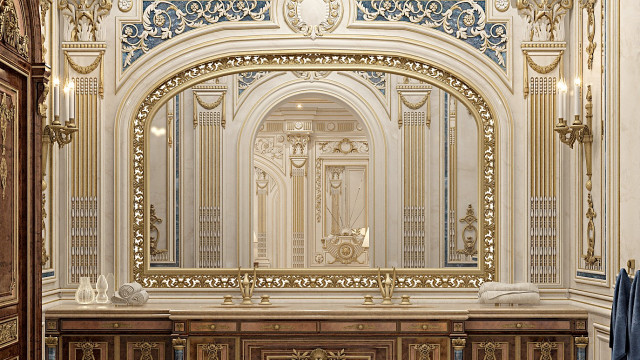 This picture shows a luxurious and modern dining room. The walls are painted in deep, dark red and are adorned with gold accents and an intricate golden mirror. The floor is a light tiled marble and the ceiling boasts an intricately-crafted chandelier. The dining table is large and rectangular, covered in a white cloth, adorned with a stunning flower arrangement and set with elegant matching chairs. On either side of the dining table are two matching sideboards, with dishes and other decorative items on display.