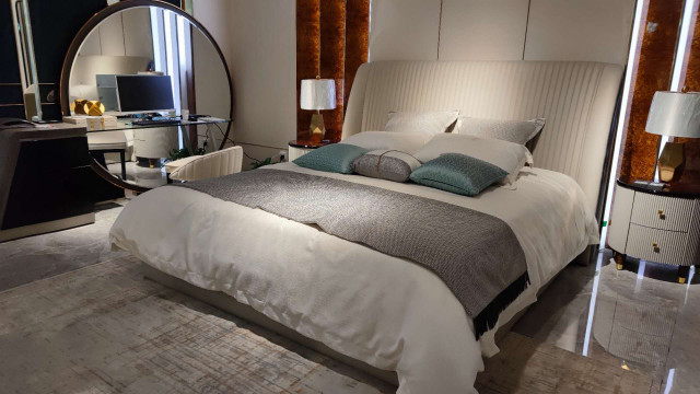 A luxurious bedroom with rich textiles, high-quality furniture, and a stunning view of the cityscape.