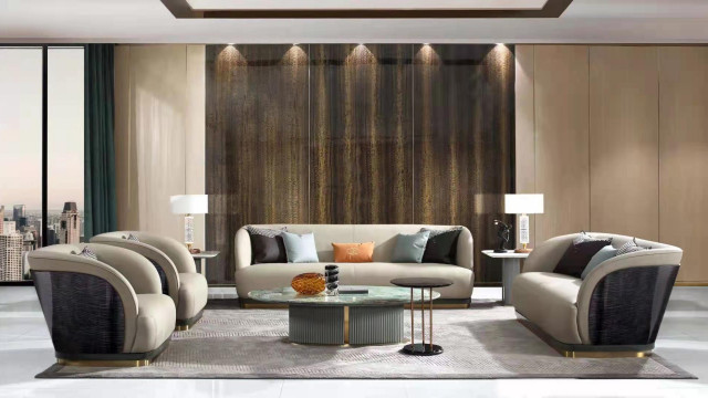 This is an interior design for a luxury foyer. It has a luxurious black and white color palette with a hint of gold. There are two bedrooms and a large open plan living room/dining area with a modern fireplace. The ceiling is high and decorated with intricate designs, and the lighting is from recessed ceiling lights as well as chandeliers. In the center of the space there is a grand staircase that leads to the upper level. On each side of the staircase there are two large white marble columns that provide a striking contrast to the dark walls and the furniture items.