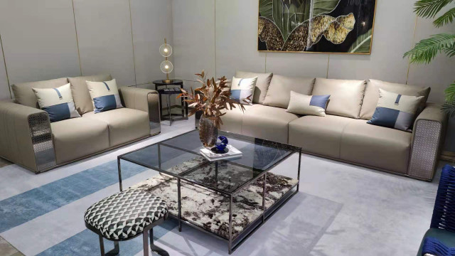 This picture shows an interior design project by Antonovich Design. It features an elegant living room with a grey sofa, two armchairs and a grey center table. The room also has a white rug and a beige wall with two arched windows and white curtains. The furniture is upholstered in a colour combination of greys and whites which creates a cozy and inviting atmosphere. The walls are decorated with contemporary art pieces and a mirror adding a modern touch to the classic look of the room.