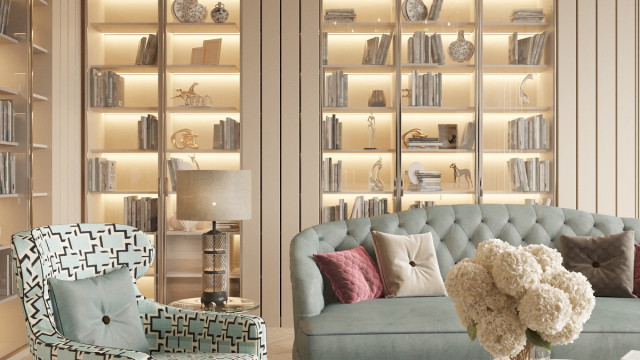 This picture shows a luxurious interior design by Antonovich Design. The room features a large curved sectional sofa upholstered in cream velvet and flanked by a pair of matching armchairs. On the opposite side is a round glass coffee table with a matching ottoman. The walls are painted an off-white and feature an ornate mirror above a fireplace. A white shag rug provides a soft floor covering and warm, inviting lighting completes the look.