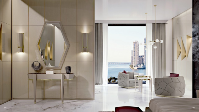 This picture shows an elegant, contemporary living room. The walls are painted a soft off-white color and feature two large windows with cream drapery, which adds to the air of sophistication. The furniture is a combination of white and dark wood tones, with the light-colored sofa creating an interesting contrast to the dark, glossy cabinet and wooden table. The tiled fireplace is surrounded by artwork, adding a cozy atmosphere to the space. A modern, glass chandelier hangs from the ceiling, completing the stylish, luxurious feel.