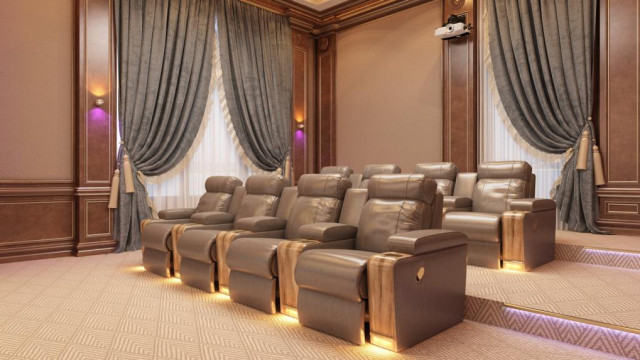 This picture shows an interior design of a modern living room. The room features a beige couch and loveseat, along with multiple patterned throw pillows and a blanket on the loveseat. There is a matching beige armchair in the corner of the room, as well as two fuzzy white side chairs. The walls and floors have a light wood finish, and there is a large contemporary art piece above the couch. On the walls are multiple shelves filled with books, knick-knacks, and plants, while the windows are dressed with sheer curtains.