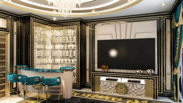 This picture shows an interior design in a spacious, opulent living room with a curved white leather sofa backed by a modern design curtain wall. The space is heavily furnished with other black and gold accents, including a grandiose crystal chandelier and mirrored side tables. The walls are painted in a dark, regal blue that is complemented by the accents of the room.