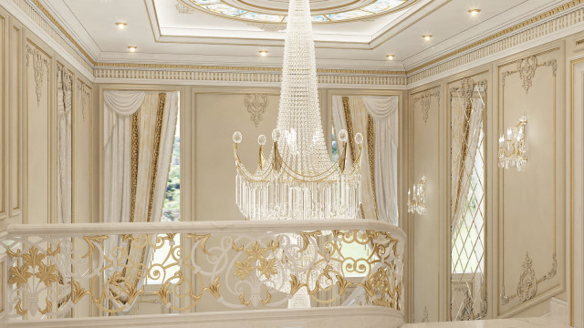 A grand double staircase with curved balustrade, intricately designed with black wrought iron and ornate railings, leading up to a large hall illuminated by a gilded chandelier.