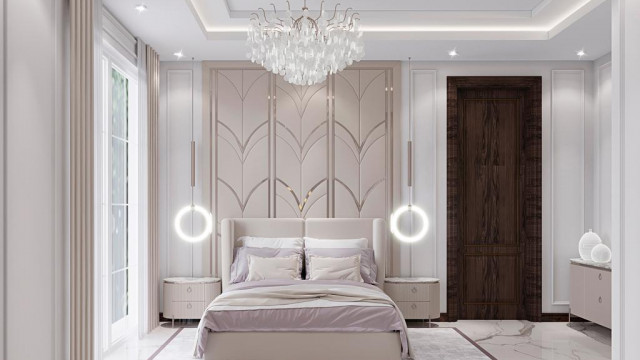 This is a picture of an opulent, modern bedroom design by Antonovich Design. It features a four-poster bed in the center, draped with sheer curtains for a romantic touch. The walls are patterned with geometric gold accents that make the room stand out. There is a luxurious, ivory-colored leather armchair on one side and two white armchairs next to a glass coffee table with gold legs on the other side. A white and gold chandelier hangs from the ceiling and several decorative pillows are displayed on the bed.