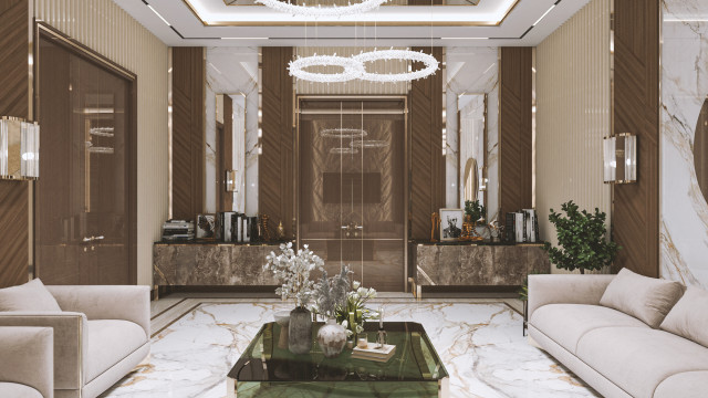 A grand and luxurious antechamber, featuring intricate carvings and detailing along the walls, columns, and ceilings; expansive marble flooring adorned with a vibrant area rug; and opulent furnishings, including plush seating and a regal chandelier.