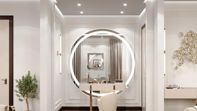 This picture shows an exquisite luxury kitchen design with dark wood cabinets, marble countertops, a large island, and a beautiful backsplash featuring intricate mosaic tilework. The white walls are accented with gold accents, making the room feel warm and inviting. The electric range and hood add a modern touch to the classic design.