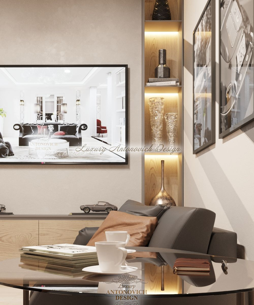 This picture shows a luxurious, modern living room with a large seating area. The focal point of the room is the stone wall with an automatic fireplace built into it. The walls are painted in a neutral white, tan, and gold tone, and the hardwood floor has a light color to match. There is a large, intricate chandelier hanging from the ceiling, while the furniture consists of plush sofas, coffee tables, and side chairs. Several rugs are scattered throughout the room, and two tall house plants in matching white pots provide additional décor.