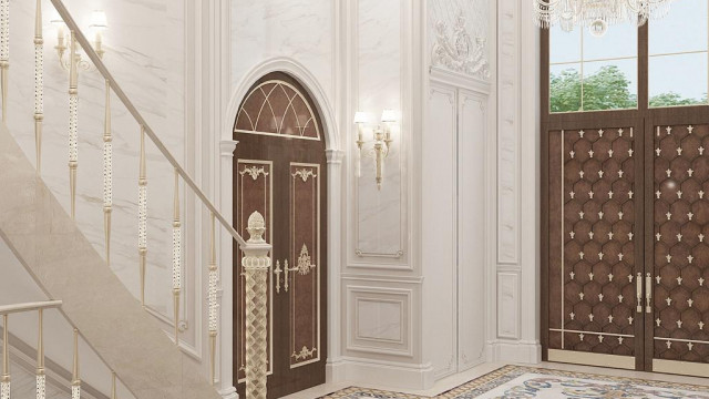 A luxurious living room with golden details, a white chair, and a wide glass wall that opens to the elegant garden outside.