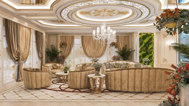 This image shows a modern living room space with luxurious and contemporary decor. The walls are painted a light gray color, and the ceiling features a geometric pattern of white crown molding. In the center of the room is a white, leather sectional sofa that faces a glass coffee table and two matching armchairs. For added comfort, there is a white area rug on the floor and unique wall art on the walls. There are also recessed lights in the ceiling for ambient lighting.