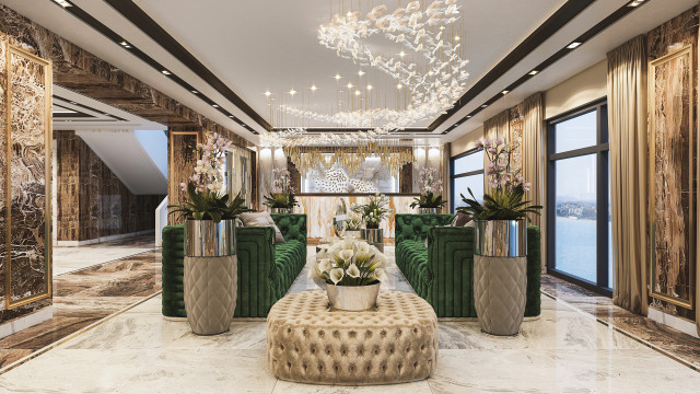 This picture shows a luxurious and modern living room. The room is decorated in neutral whites and beiges, with a large area rug in the center of the room, a white couch against one wall, two chairs in the corner, and a beige ottoman in the middle. On the walls are several pieces of art, and above the couch hangs a large, decorative chandelier. There is a stone fire place in the corner with intricately carved mantle above it. The room also has tall windows with light-filtering window treatments.