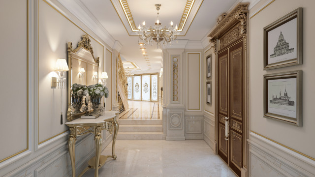 This picture shows a luxurious master bedroom. The walls are painted in a cream color, and the furniture is in cream, gold, and black. The bed is on a platform, with a large headboard and luxurious linens. There are chairs beside the bed for extra seating, and a chaise lounge for relaxation. A wardrobe is placed against one of the walls, and there are two nightstands with lamps flanking the bed. An intricately patterned rug covers the floor, and a large round mirror hangs above the bed.