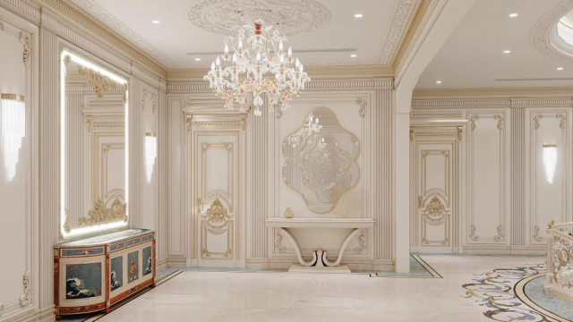 This picture shows a luxurious living room in an interior design project. The room has a modern and elegant style, with a symmetrical design featuring a white marble floor, pale pink walls, and white furniture. The main statement piece in the room is an impressive white marble fireplace with intricate carving detail. On either side of the fireplace are two large armchairs upholstered in a cream-colored fabric. The space is also filled with ornate pieces of décor such as gilded frames and vases. Soft light is provided by two sets of wall lamps that flank a white marble