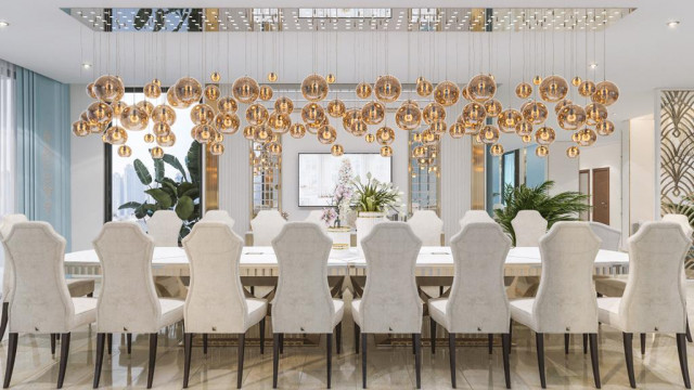 This picture shows a luxurious living room with a modern design. The walls and ceiling feature intricate architectural detailing and moldings. The colors are neutral, with white as the primary hue. The flooring is white marble, and there are two dark velvet sofas with a persian rug between them. The centerpiece of the room is a large contemporary chandelier, which stands out against the white walls. On either side of the room, tall windows let in plenty of natural light, making the room bright and inviting.