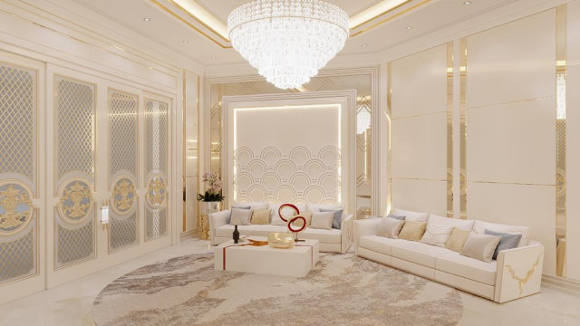 This picture shows a beautiful and luxurious interior design with an elegant entryway. The room features cream-colored walls with a warm wooden flooring, light fixtures, and furniture pieces. The walls feature abstract art pieces in black frames, and the walls are complemented by white trim. A large, round mirror is mounted on one wall, and a decorative rug lies on the floor near the front door.