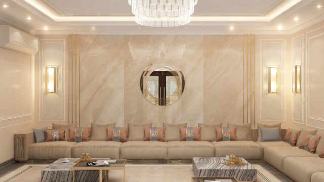 This picture shows a luxurious living space with dark marble flooring, an elegant round table in the center, a white sofa against one wall, and two armchairs upholstered in beige fabric. There is also a matching ottoman and a unique curved console table with decorative accents. The room has an elaborate crystal chandelier and a round mirror mounted on the wall to enhance the lighting. The large windows are covered in white curtains, and on the opposite wall, there is a grand fireplace with a mantelpiece decorated with art pieces.