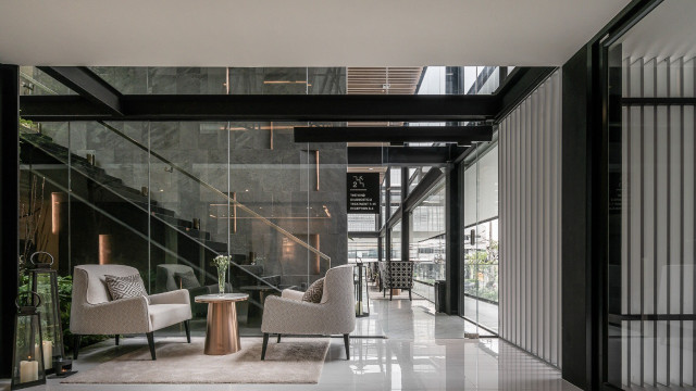 This picture shows an exquisite, custom designed staircase in a luxurious, modern home. The staircase is made of high-quality marble, with a curved, spiraling shape and ornate decorative railings. The walls of the stairwell are adorned with framed artwork, while a large skylight fills the space with natural light.