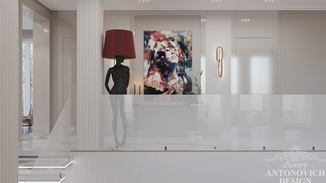 This picture shows a luxurious modern style living room. There are several pieces of stylish furniture, such as a white tufted leather sofa, a glass coffee table, and a grey armchair. The walls are decorated with neutral colored wallpaper, and there are several abstract art pieces featured on the wall. The hardwood flooring is polished and there is an area rug in the center of the room. Overall, this living room has a high-end look that exudes sophistication and comfort.