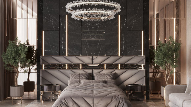 A luxurious bedroom featuring a bed upholstered in velvet fabric with studded appliqués and a tufted headboard, complemented by elaborate gold trim detailing on the walls.