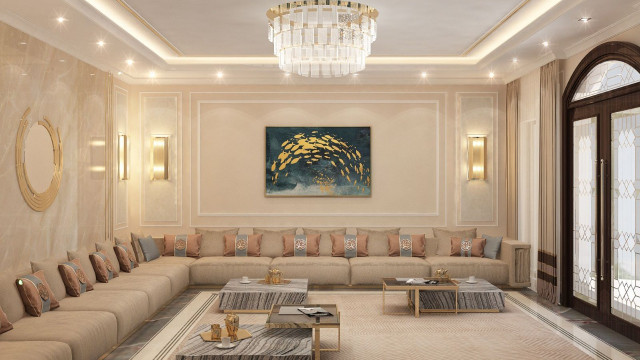 This picture shows a modern living room designed by Antonovich Design. It features a stylish L-shaped sectional sofa upholstered in light grey fabric and flanked by two white accent chairs. The room also has a sleek coffee table with two ottomans, a white marble fireplace, and a large panel wall art. In addition, the room is surrounded with floor-to-ceiling windows that allow plenty of natural light to enter the space. The overall design is modern and minimalistic, creating an inviting and luxurious atmosphere.