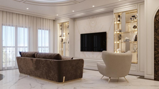 A large, luxurious living space featuring an ornately decorated interior including a white chaise lounge, comfortable armchairs, and a crystal chandelier.